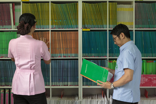 Staff at the Taldeaw Health Promotion Hospital organize their files - they keep colour-coded files for each village they serve. Khaeng Koi district, Saraburi province, Thailand. August 2019.