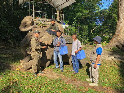 Mr Tage Mali (extreme left), forest officer, Miao circle, Namdapha National Park and Tiger Reserve, and Dr Jongsam Handsome (extreme right), medical officer in-charge, Miao sub-division, Changlang district, brief vaccinators before they begin their elephant ride across the Noa-Dihing river to Ayushman Bharat Health & Wellness Centre Deban. The elephant Lakhi sits patiently with her nephew Samraj, 13, who is getting ready to head off for forest patrolling.  